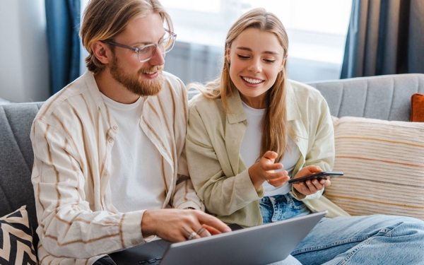 Een stel zit samen op de bank en doet een betaling op de laptop