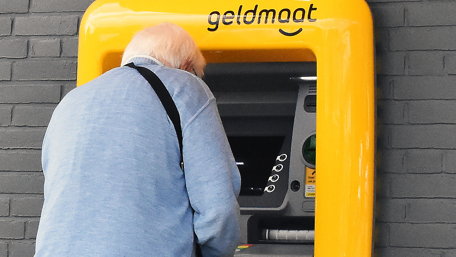 Senior aan het pinnen bij geldautomaat